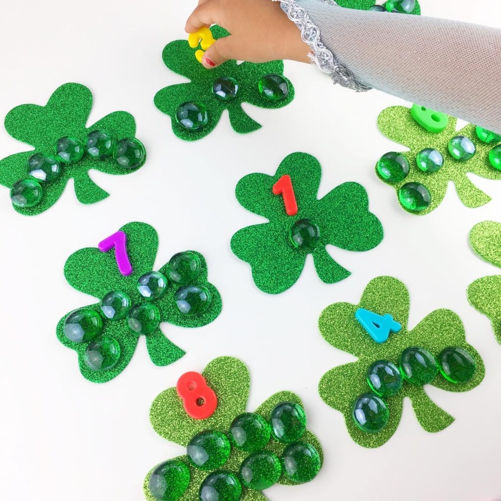 girl placing number three on a shamrock with three glass gems on top