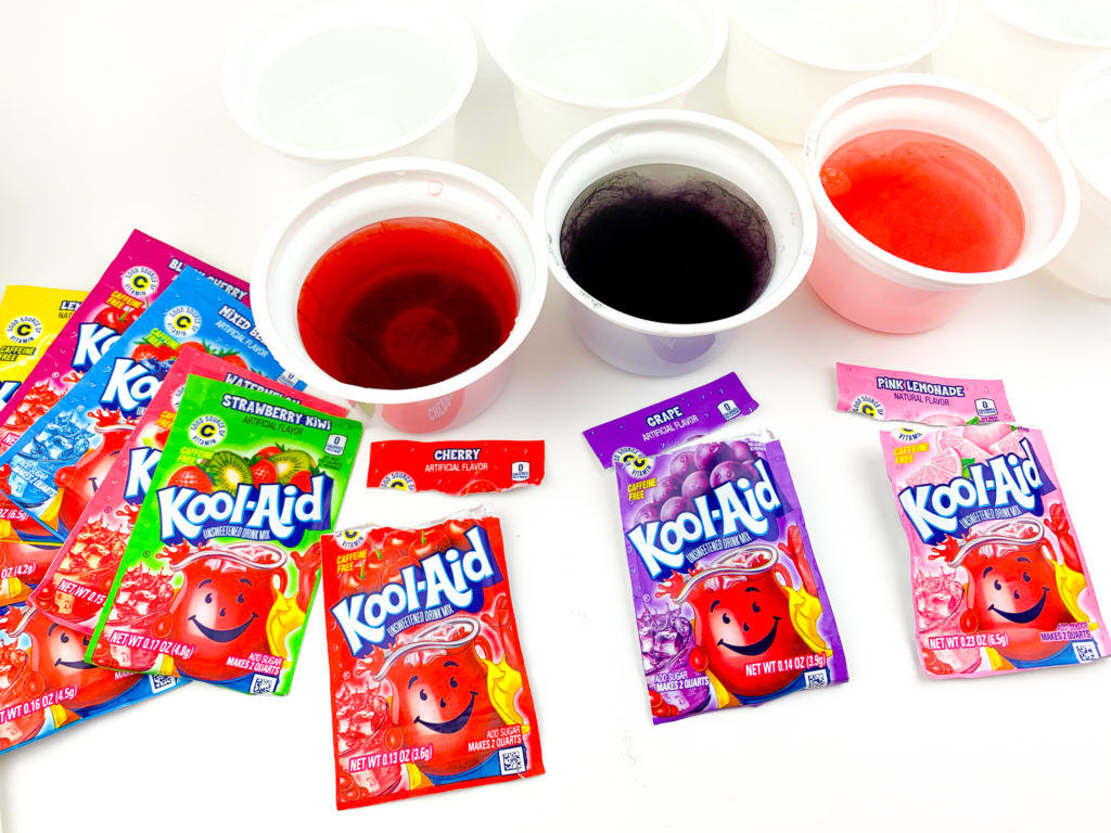 three recycled yogurt cups filled with water and Kool-Aid mixed together