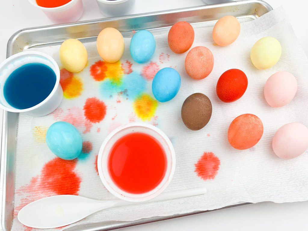 14 Kool-Aid-dyed Easter eggs drying on a paper towel-lined pan