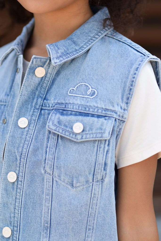 Petite Revery brand cream cotton shirt under blue jean vest embroidered with a cloud.