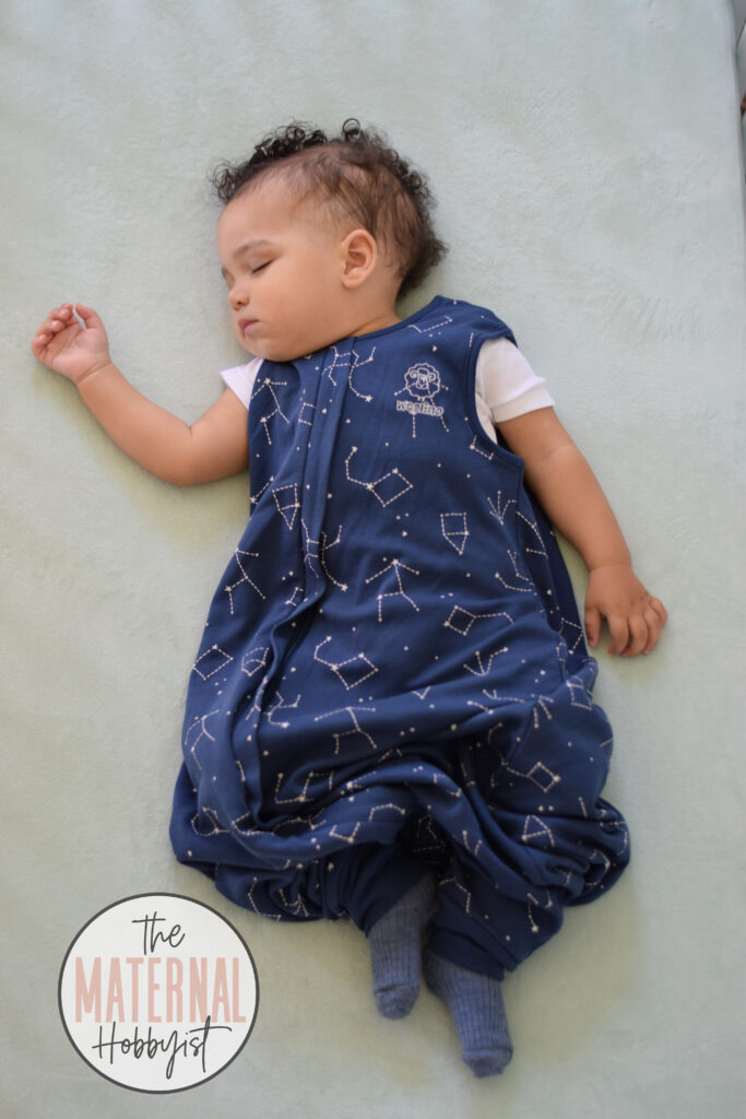 baby sleeping while wearing a blue wool sleep sack and wool socks in a crib.
