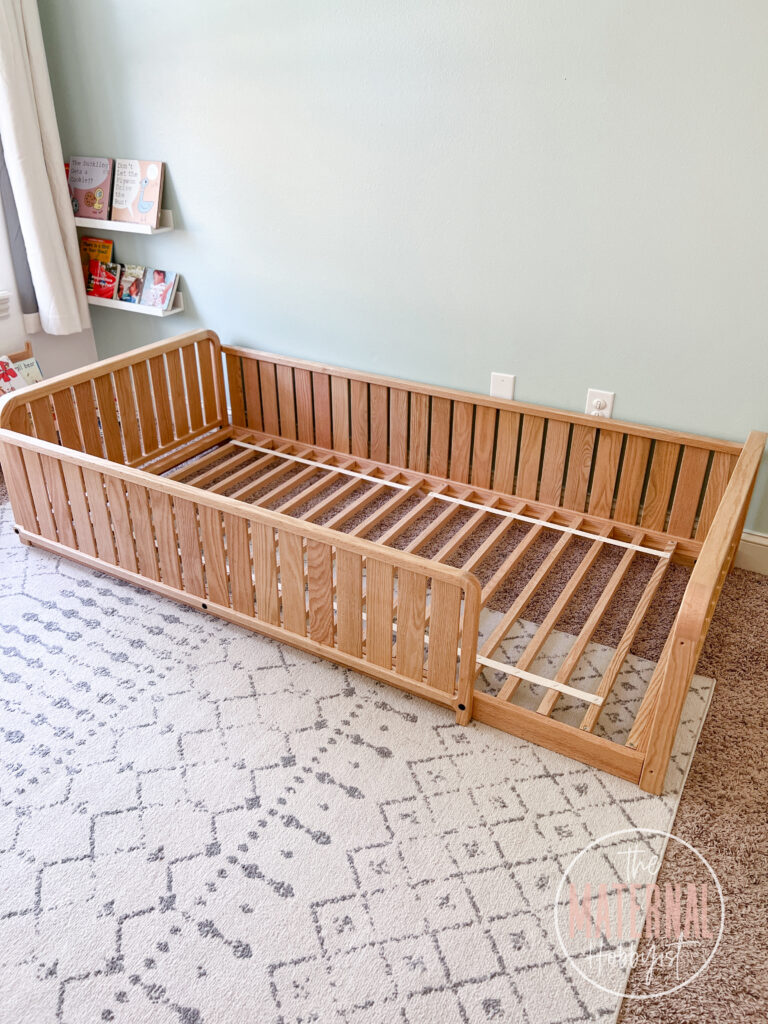 Brown Sosta Montessori floor bed frame sitting on a Moroccan area rug.
