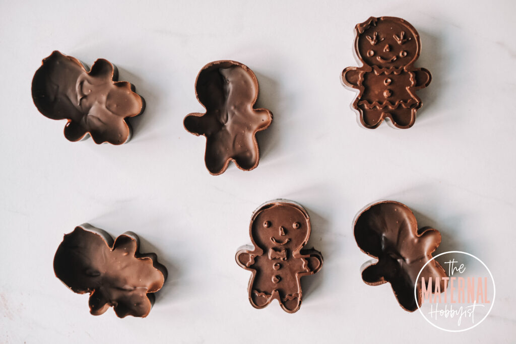 six chocolate gingerbread shaped halves laying on a white counter