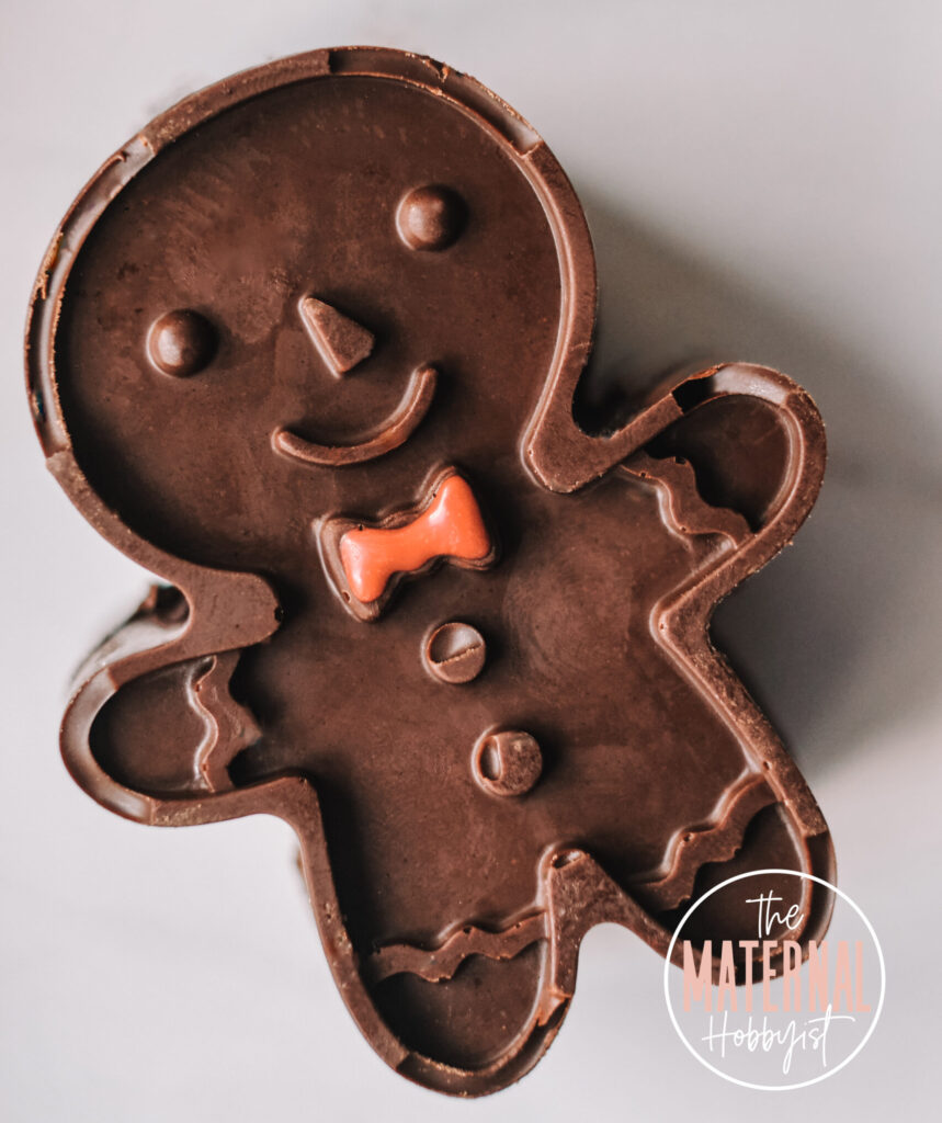 chocolate gingerbread shaped hot cocoa bomb with a red chocolate bow tie