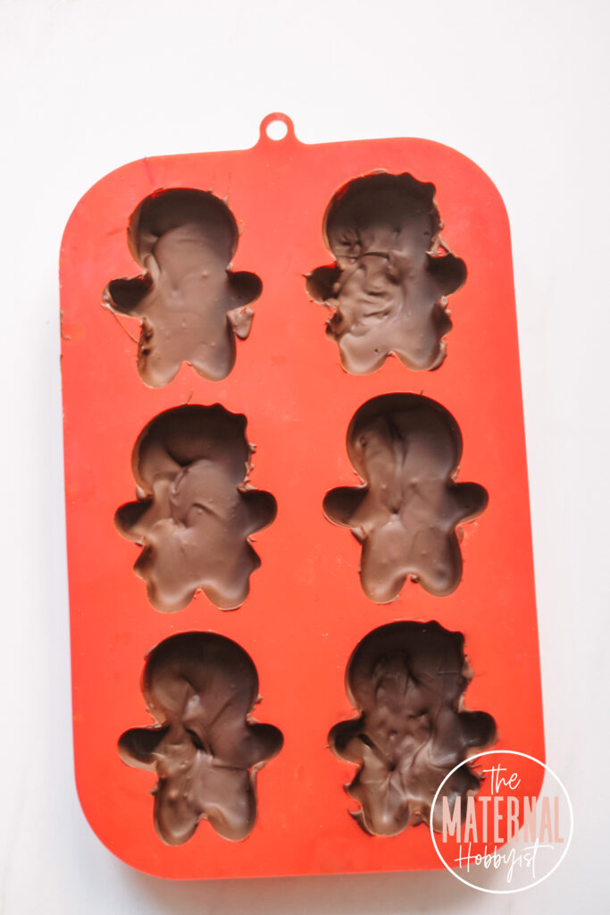 red silicone mold with six gingerbread shapes filled with chocolate