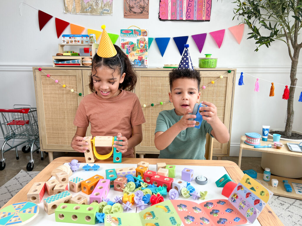 An 8 year old girl and a 4 year old boy playing with Melissa & Doug Blockables on a kids table.