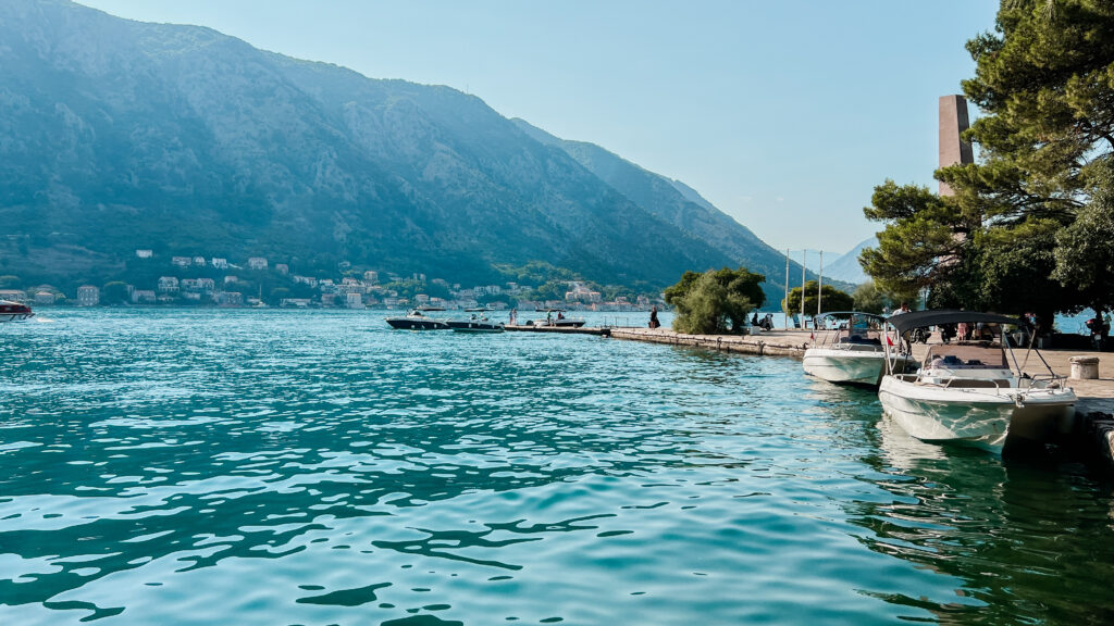 Boats floating near the dock in Kotor Bay in front of the mountains